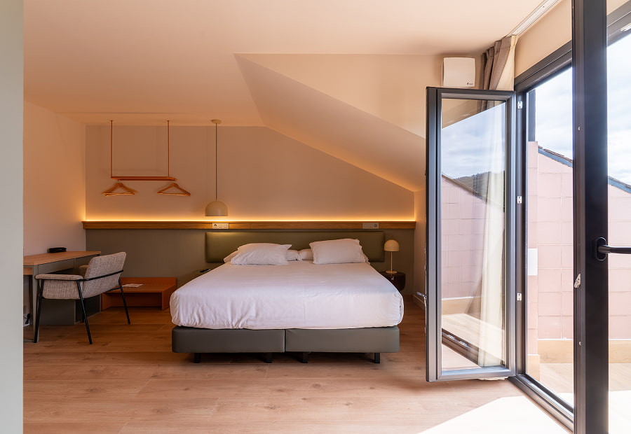 Habitación triple superior con cama King size, escritorio, balcón y lámparas de diseño